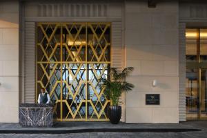 ドーハにあるWaldorf Astoria Doha West Bayの建物前に立つ男