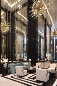 a lobby with chairs and tables and chandeliers at Waldorf Astoria Doha West Bay in Doha