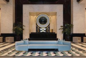 a blue couch in front of a building with a clock at Waldorf Astoria Doha West Bay in Doha