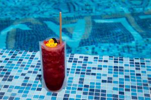 a drink sitting on a table next to a swimming pool at Camino Real Fashion Drive Monterrey in Monterrey