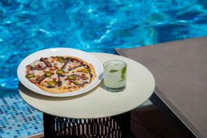 una pizza y una bebida en una mesa junto a una piscina en Camino Real Fashion Drive Monterrey, en Monterrey