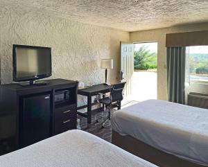 a hotel room with two beds and a desk with a television at Quality Inn in Clinton