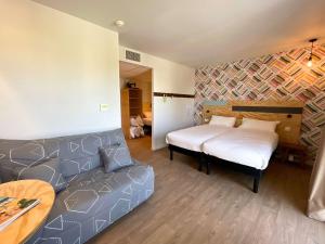 a living room with a bed and a couch at greet hotel Castets Coeur des Landes in Castets