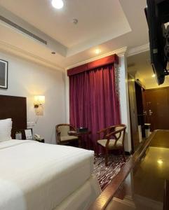 Habitación de hotel con cama y cortina roja en Carawan Al Khaleej Hotel Olaya en Riad