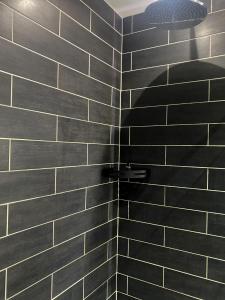 a black tiled shower with a light in a bathroom at The Midway in Adlington