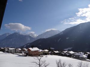 uma aldeia na neve com montanhas ao fundo em Ferienhaus Mattersberger em Oberlienz