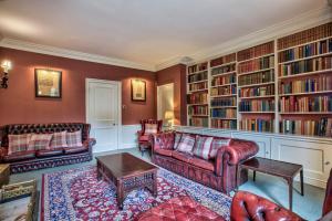 ein Wohnzimmer mit roten Möbeln und Bücherregalen in der Unterkunft Abbey House by Group Retreats in Saffron Walden