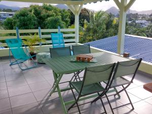 a green table and chairs on a patio at Calme Villa in Sainte-Rose