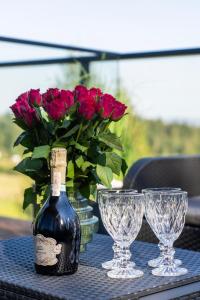 una bottiglia di vino e due bicchieri su un tavolo con rose di Apartament Magiczne Podhale by Apart Concept Podhale a Kościelisko