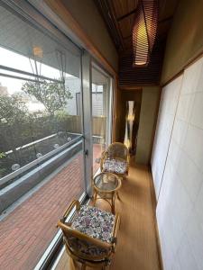 a balcony with two chairs and a large window at アンドステイ中野弥生町 in Tokyo