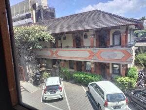 dos coches estacionados frente a un edificio en Hotel Grand Kumala Bali en Legian