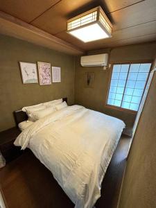 a bedroom with a large white bed with a window at アンドステイ中野弥生町 in Tokyo