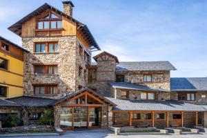 un gran edificio de piedra con techo en Abba Ordino Babot Hotel en Ordino