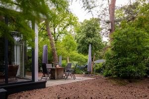 a patio with a table and chairs and trees at Lodge IJsvogel Nunspeet Veluwe in Nunspeet