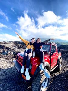 two women sitting on the back of a red jeep at D Khaylas in Kintamani
