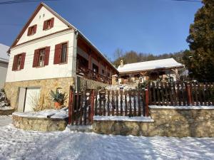 a house with a fence in the snow at Bauer Vendégház Püspökszentlászló in Hosszúhétény-Szőlőhegy