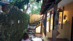 een vrouw die voor een muur zit bij Ca'n Solar 2 in Búzios