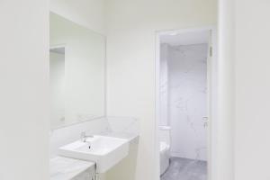 Baño blanco con lavabo y aseo en OYO Life 1830 Mandala Residence, en Yakarta