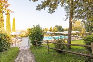 una piscina con mesas y sombrillas junto a una valla en Appartamento Aleatico, en Montepulciano