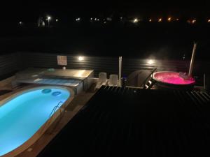 a swimming pool at night with a hot tub at Vila Lorena in Stejaru