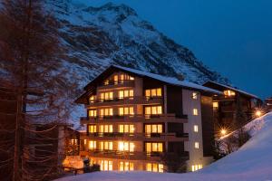 un bâtiment dans la neige devant une montagne dans l'établissement BaseCamp Hotel, à Zermatt