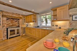 a kitchen with wooden cabinets and a brick wall at Finest Retreats - The Old Coach House in Stony Stratford