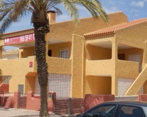ein gelbes Gebäude mit einer Palme davor in der Unterkunft Taravilla 26 2 dormitorios 1 in Puerto de Mazarrón