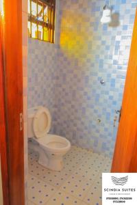 a bathroom with a toilet in a blue tiled room at Scindia Suites hotel in Jinja