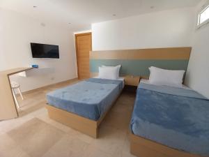 a hotel room with two beds and a desk at Nayah Stays, Ground terraces Studio in Hurghada