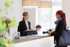 two women standing at a counter talking to a girl at Hotel Hinrichs in Carolinensiel