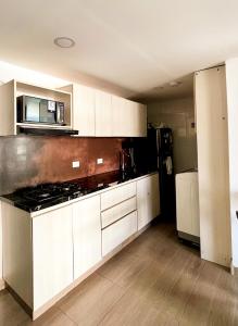 a kitchen with white cabinets and a stove top oven at Polanco Residences Tocagua Cartagena - Colombia in Cartagena de Indias