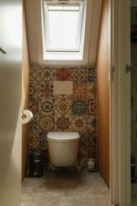 Un baño con inodoro y ventana. en Vrijvakantiehuis Duinweg 2b, en Oostkapelle