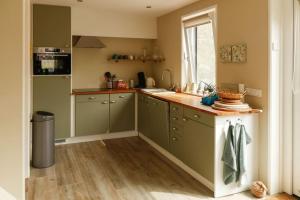 cocina con armarios verdes y encimera en Vrijvakantiehuis Duinweg 2b, en Oostkapelle 23 fotos más