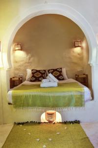 a bedroom with a bed in a room with an arch at Dar Shams in Erriadh