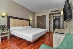 - une chambre avec un grand lit blanc et une télévision dans l'établissement Hotel Zaragoza Royal, à Saragosse