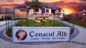 a sign in front of a house with a yard at Conacul Alb, prilej de vacanță 