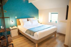 1 dormitorio con 1 cama con pared azul en Les clés de la ferme - 4 chambres - proche La Loupe et Nogent-le-Rotrou - option SPA, en Sablons-sur-Huisne