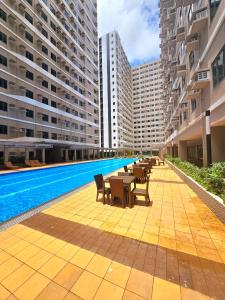 uma piscina no meio de um edifício com mesas e cadeiras em Acellyne Suites at Green 2 Residences with Netflix! em Dasmariñas