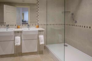 a bathroom with two sinks and a glass shower at Old Hunstanton Le Strange Arms Hotel in Hunstanton