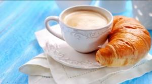 a cup of coffee and a croissant on a plate at Girasole room Sperlongaresort in Sperlonga