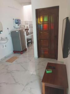 Cette chambre comprend un réfrigérateur, une table et une porte. dans l'établissement Tree shadow Guest house nearby Beach, à Mahabalipuram