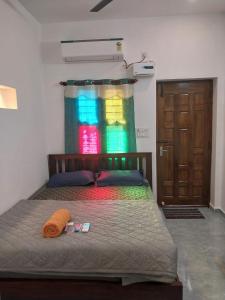 Un dormitorio con una cama con una cortina de colores y una puerta en Tree shadow Guest house nearby Beach, en Mahabalipuram