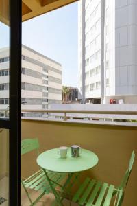 einen Tisch und zwei Stühle und eine Kaffeetasse am Fenster in der Unterkunft Cosy 1BR near Beach by FeelHome in Tel Aviv
