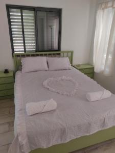 een bed met twee witte handdoeken en een hart erop bij פנינה בראש פינה in Rosh Pinna