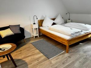 ein Schlafzimmer mit einem Bett, einem Sofa und einem Stuhl in der Unterkunft Fischerklause am Lutjensee in Lütjensee