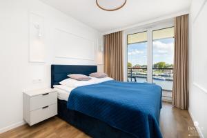 a bedroom with a blue bed with a view of the water at Lighthouse Mrzeżyno - Jantar Apartamenty in Mrzeżyno