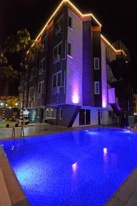 a swimming pool in front of a building at night at La Rezidans Hotel in Antalya