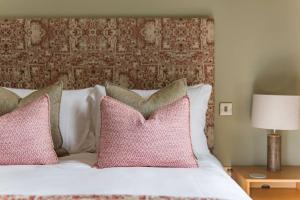 a bedroom with a bed with pink pillows at The Old Cherry Barn - Luxury barn conversion in Faversham