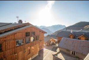 a group of wooden buildings with mountains in the background at Chalet 2 sur la route du tour in LʼHuez