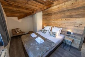 a bed in a room with a wooden wall at Chalet 2 sur la route du tour in LʼHuez